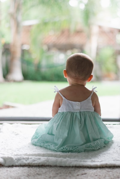 选择性聚焦照片，幼儿穿着无袖连衣裙坐在地板上